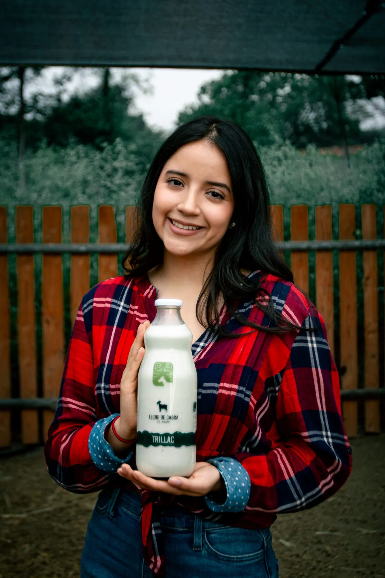 Mujer sonriente sostiene una botella de vidrio de Leche de Cabra Trillac